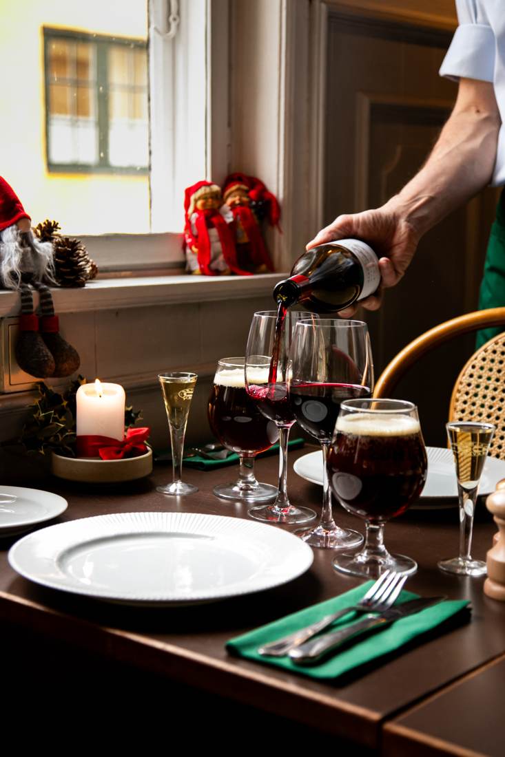 Rødvin skænkes ved julebordet med lys, nisser og juleøl