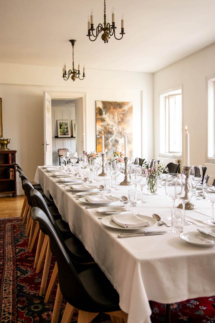 Langbord med lysekroner dækket til fest på Beghuset