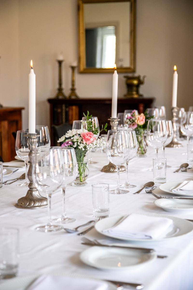 Langbord med lys, vinglas og friske blomster i Beghusets sal på første sal