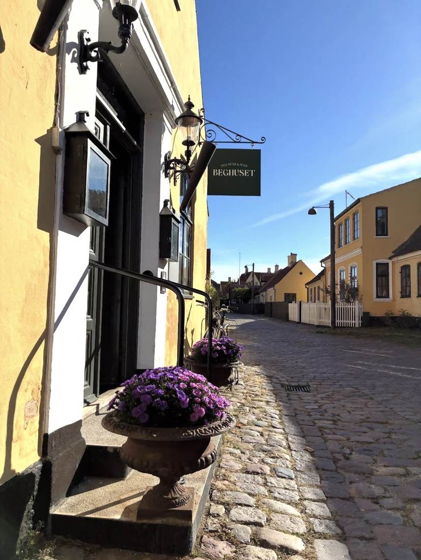Beghusets skilt over en brostensbelagt gade i Dragør